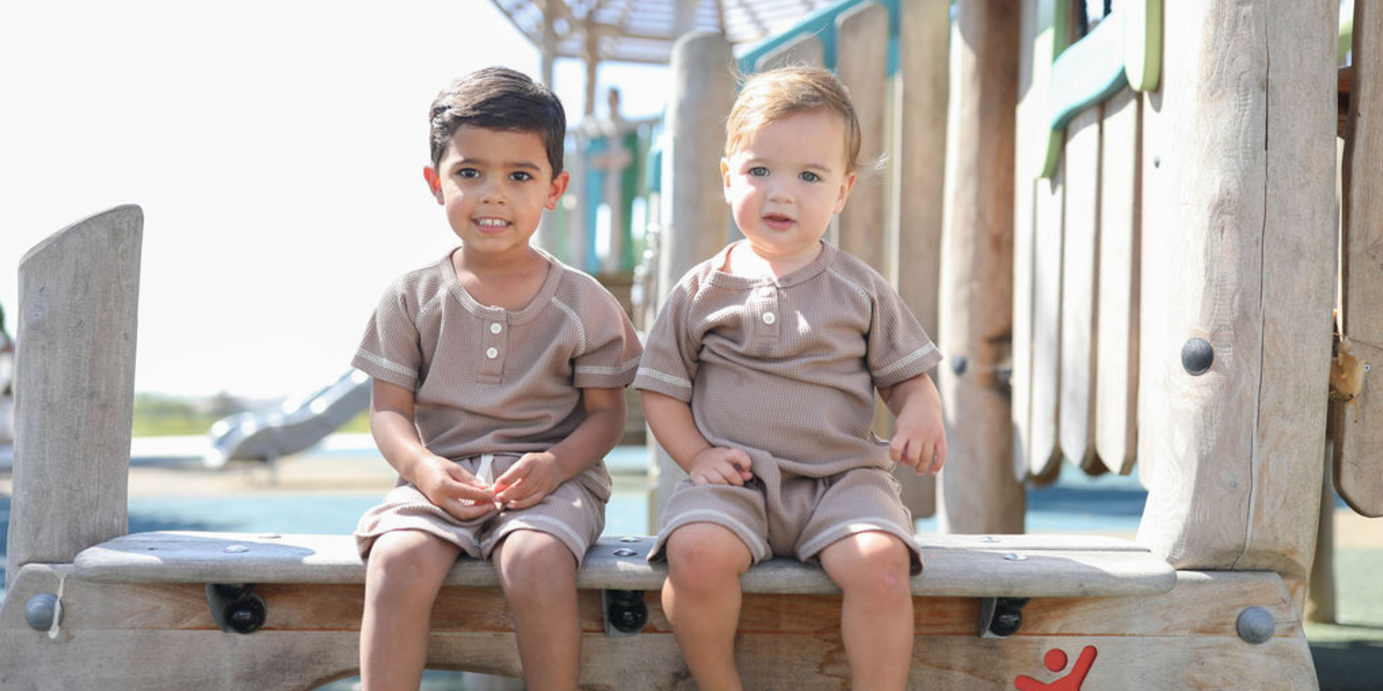 Two children sitting on a playground structure with a blurred background